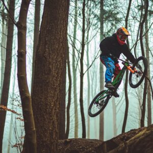 a man riding a bike through a forest filled with trees